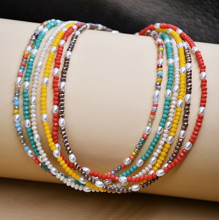 Close-up of the multi-coloured beaded necklace and matching bracelet displayed on a mannequin.