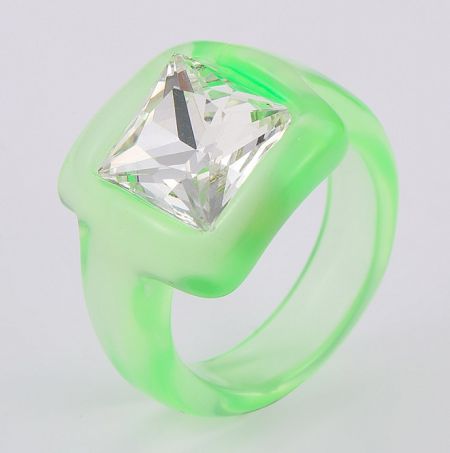 Close-up of a neon green acrylic ring featuring a large, sparkling square-cut rhinestone.