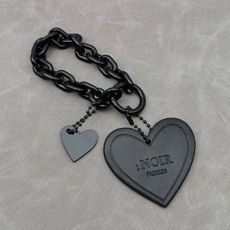 Close-up of the black PU leather heart charm with custom 'NOIR FASHION' logo embossing.