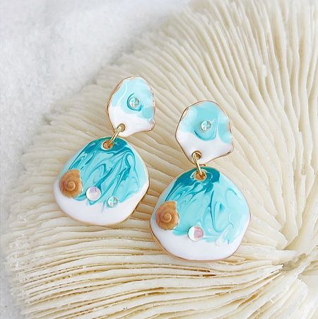 A pair of ocean-inspired earrings featuring a marbled blue and white design with delicate gold seashell decorations.