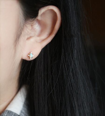 Close-up view of the opalescent stud earring being worn, showcasing its shimmer.