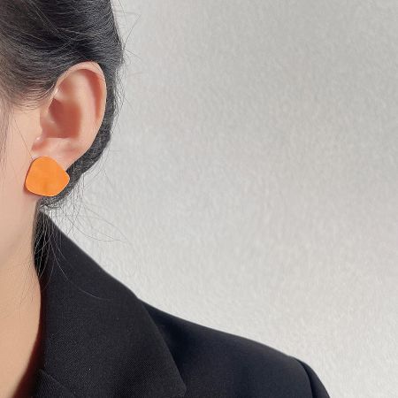 Model showcasing the orange matte enamel irregular shape stud earring.