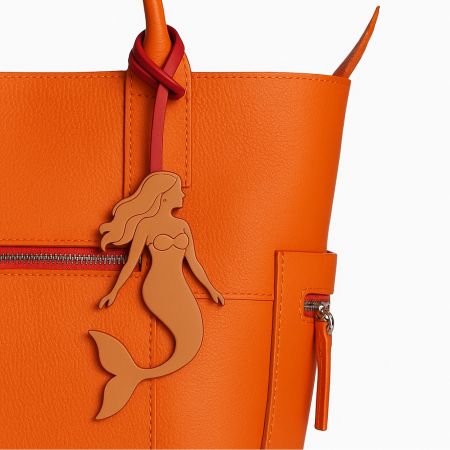 Personalised Bag Charms: Your Unique Mermaid Accessory Awaits - A custom mermaid-themed personalised leather bag charm by JR Fashion Accessories, elegantly attached to a stylish orange handbag.