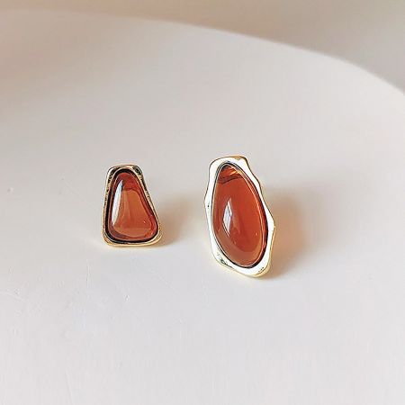 A pair of teardrop-shaped earrings with orange stones and gold settings.