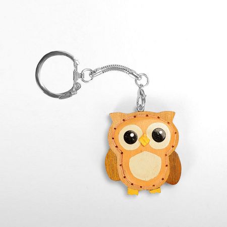 A beautifully crafted wooden owl keychain with intricate details and stitching.