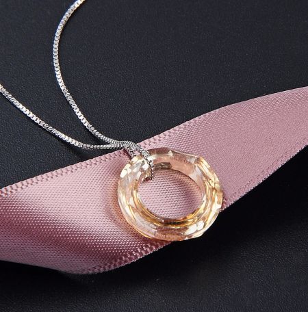 A beautiful variation of the sterling silver circle necklace with a peach-colored Swarovski crystal pendant.
