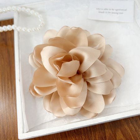 A close-up of a peach-colored rose flower hair clip presented elegantly in a white box.