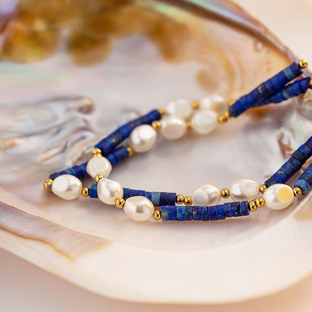 Elegant display of the pearl and blue stone bead necklace on a seashell.