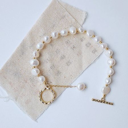 A beautifully crafted baroque freshwater pearl bracelet with gold accents and a toggle clasp, displayed on a neutral background.