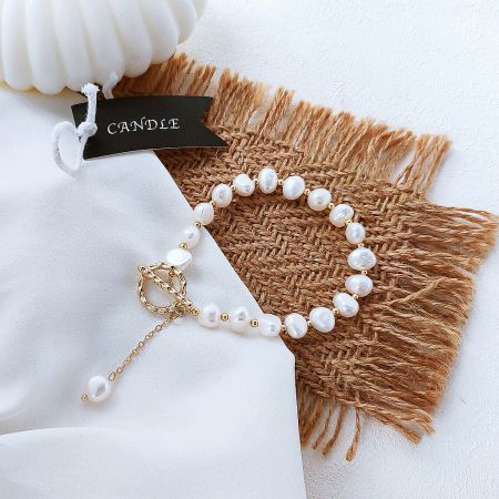 Detailed view of the toggle clasp and gold components of the baroque pearl bracelet.