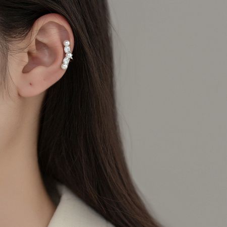Close-up of a sterling silver pearl ear cuff worn on an ear, highlighting its elegant design and comfortable fit.