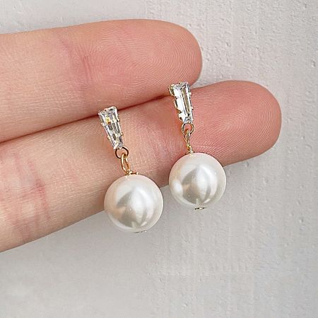 A hand holding the elegant pearl drop earring to display its size and delicate features.