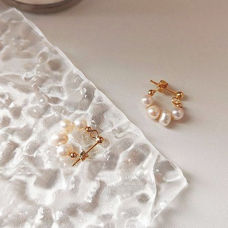 Detailed shot of the secure gold clasps on the baroque pearl earrings.