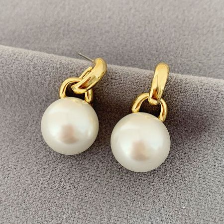 Detailed view of the pearl earrings with polished gold clasps.