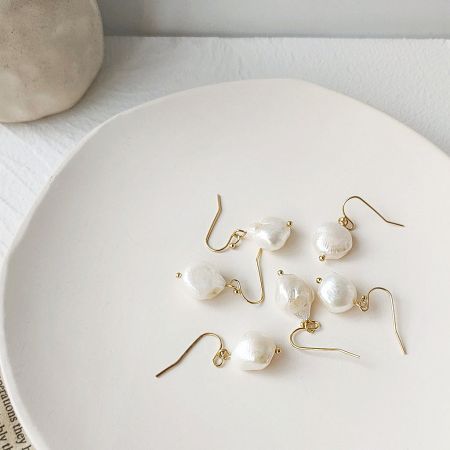 Close-up of a pair of baroque pearl earrings with elegant gold hooks.