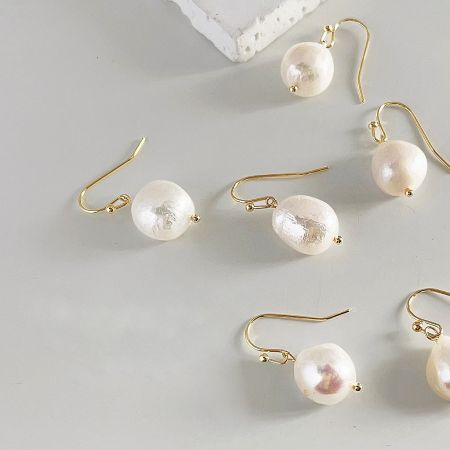 Detailed view of the lustrous baroque pearl and gold hook on the drop earrings.