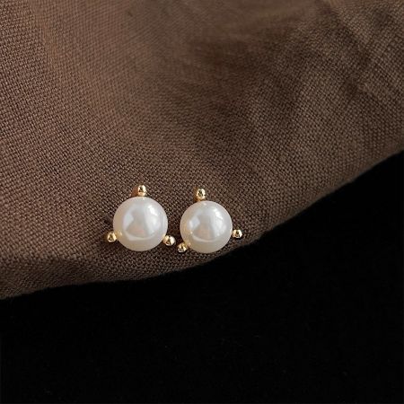 Detailed view of the gold settings on the simple pearl stud earrings.
