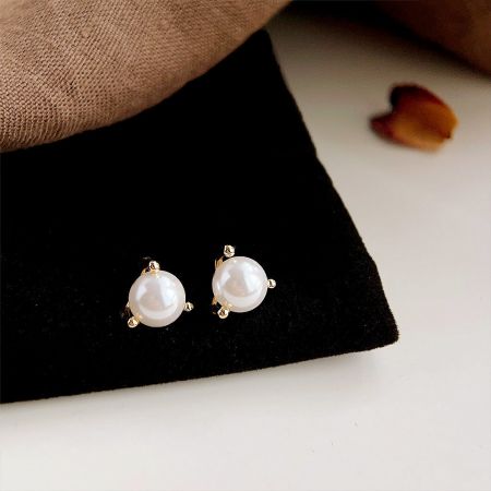 Product shot of the 14k gold plated pearl stud earrings, showing the set of five pairs.