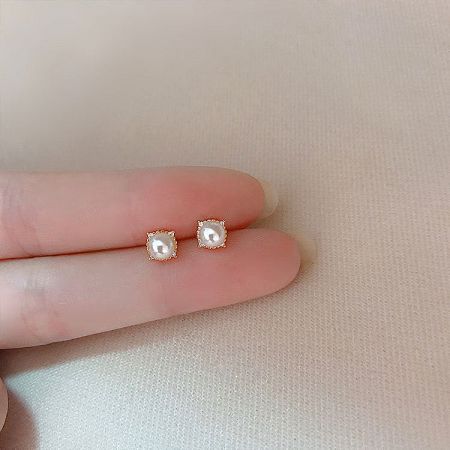 A detailed view of the pearl stud earrings in a warm rose gold setting.