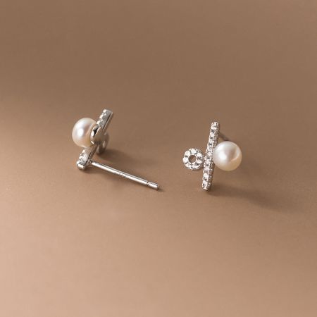Detailed shot of the modern silver pearl earrings with sparkling gemstone accents.