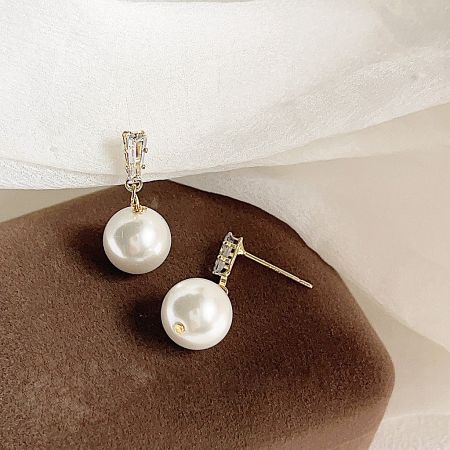 Detailed shot of the pearl drop earrings, highlighting the gold posts and sparkling crystal accents.