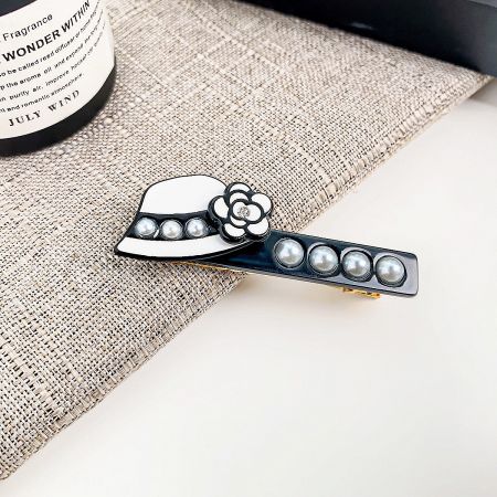 Close-up of a unique hat-shaped hair clip in white, adorned with a delicate flower and lustrous pearls.