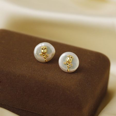 Side profile of the baroque pearl and gold flower stud earrings showcasing their dimension.