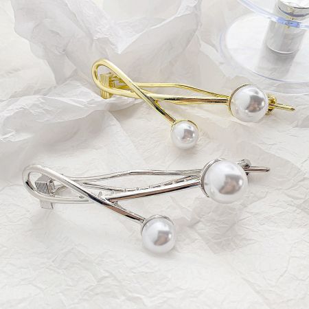 A pair of elegant twisted pearl hair clips in gold and silver finishes.