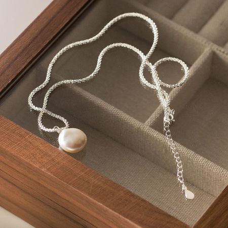 Detailed view of a single baroque pearl necklace, focusing on the lustrous pearl and the delicate silver chain.
