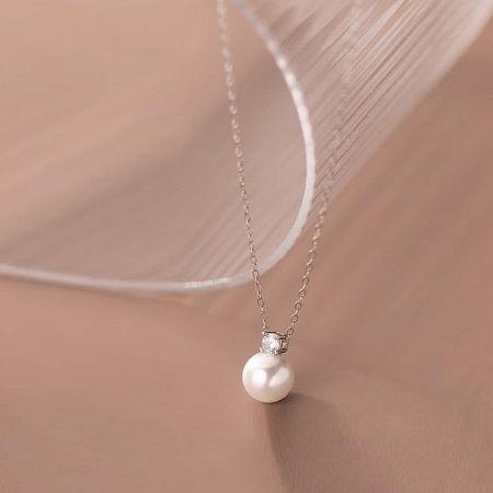 Angled view of the pearl necklace highlighting the sparkling cubic zirconia accent.