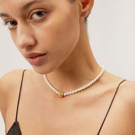 The pearl and gold bead necklace worn to display its length and drape.