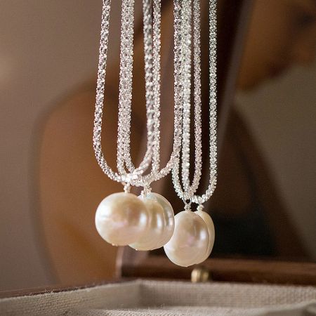 Two baroque pearl necklaces featuring intricate crystal beading on multi-strand chains.