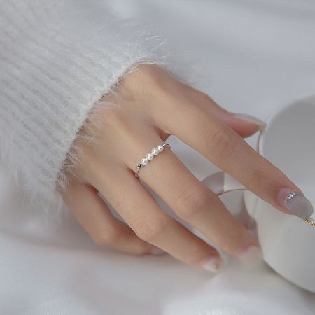 A detailed view of the adjustable pearl ring on a woman's finger, showcasing the sterling silver band.