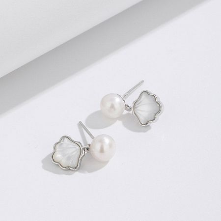 A pair of sterling silver shell and pearl drop earrings, highlighting the lustrous materials.