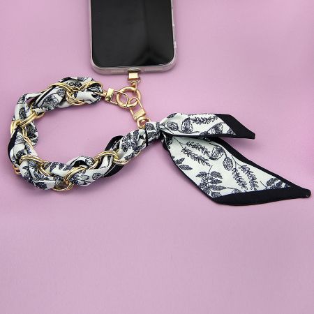 A stylish phone accessory with a vibrant floral patterned strap and gold hardware.