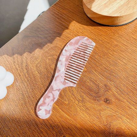A solid pink wide-tooth comb with a smooth, glossy finish.