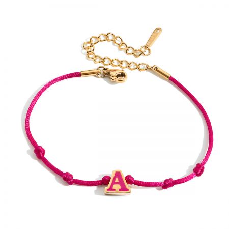 Detailed view of the pink cord friendship bracelet featuring a gold and white enamel 'A' initial charm.