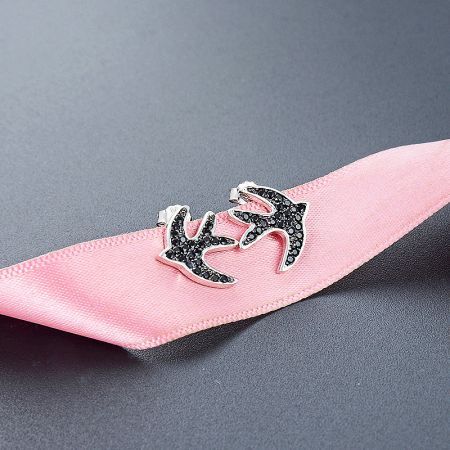 The swallow bird stud earrings presented on a branded display card, highlighting their size and elegant finish.