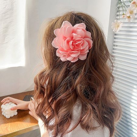 A young girl wearing the pink rose flower hair clip, suitable for all ages.