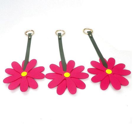 Three vibrant hot pink daisy flower keychains with green straps.