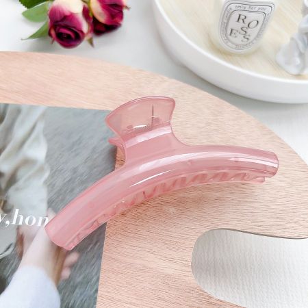 Elegant pink arc shape hair claw clip on a neutral background.