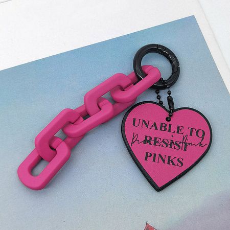 Vibrant pink PU leather heart keychain with a playful 'UNABLE TO RESIST PINKS' message.