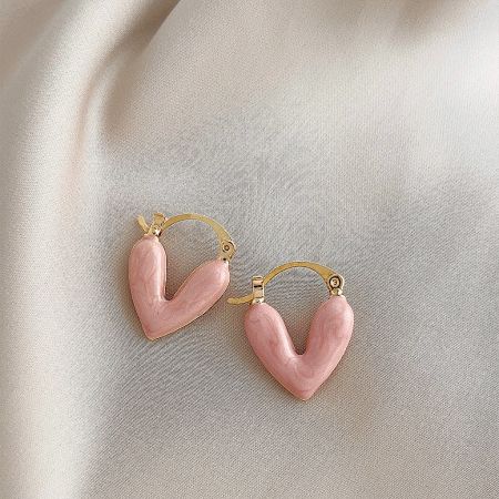 The pink enamel heart hoop earrings displayed on a textured fabric background.
