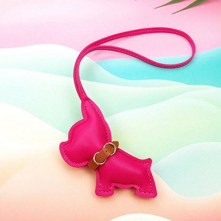 A charming pink leather dachshund keychain with a brown collar and gold buckle.