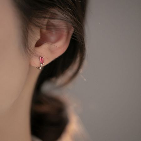 Close-up of a model wearing the pink zircon sterling silver huggie earring.