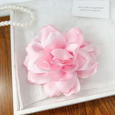 A delicate pink rose hair clip displayed next to an inspirational card.