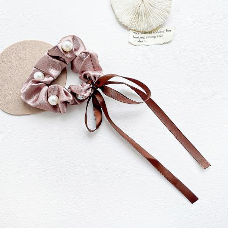 Detailed view of the pink satin scrunchie with beautiful pearl and ribbon accents.