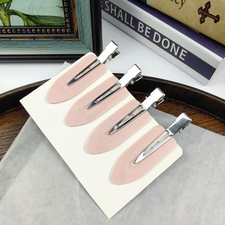 A set of four pink and silver creaseless hair clips on a white display card.