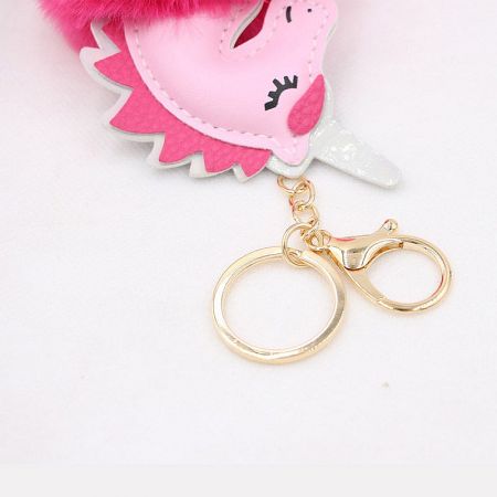Detailed view of the pink unicorn bag charm highlighting the durable gold clip attachment.