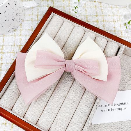 Charming pink and white ribbon bow hair clip, perfect for a soft, feminine look.